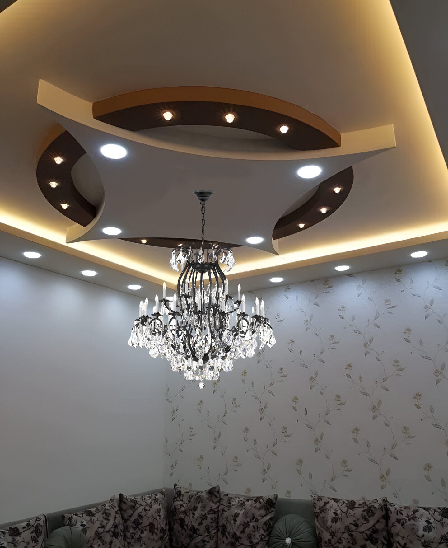 Chandelier hanging from a ceiling with decorative lighting and floral wallpaper.