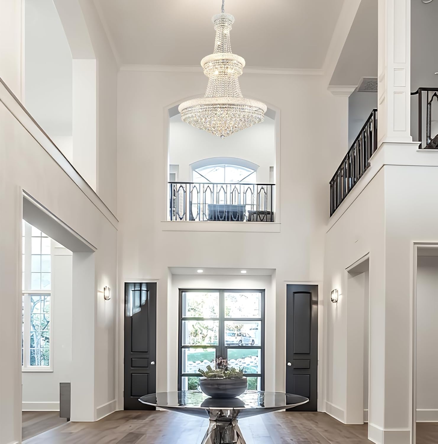 Luxurious interior of a home with a high ceiling, chandelier, and large windows.